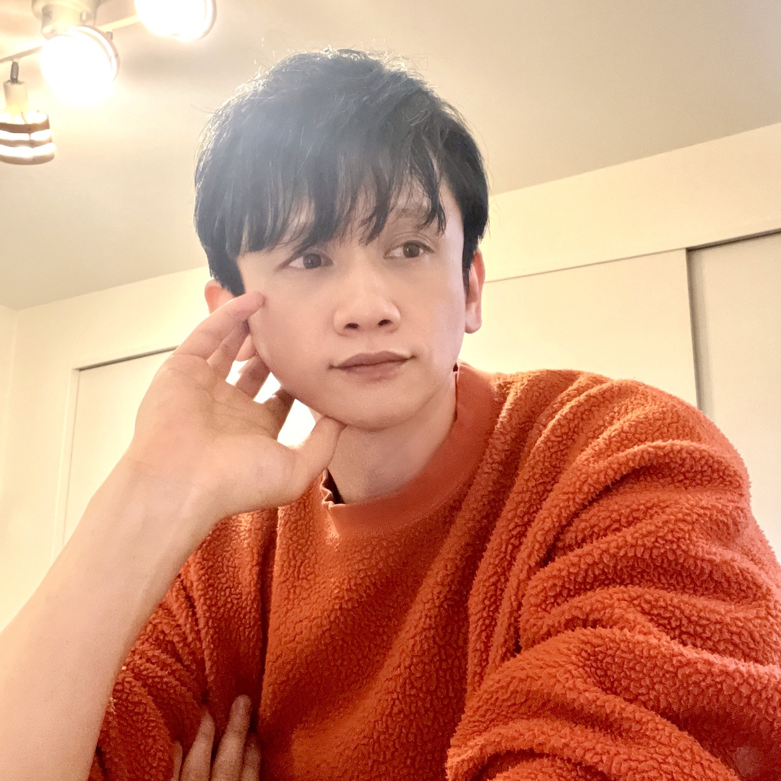 ムーンテッド(MoonTed)の日記より、頬杖をついて斜め上を見るムーンテッド(MoonTed)のセラピストAKI。オレンジのセーター姿