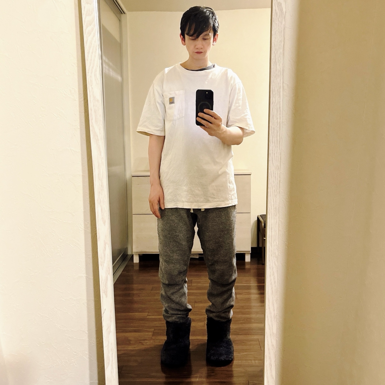 ムーンテッド（MoonTed）の日記より、鏡の前で、モフモフのルームシューズを履いて立つムーンテッド（MoonTed）のセラピストAKI。白いTシャツにグレーのパンツ
