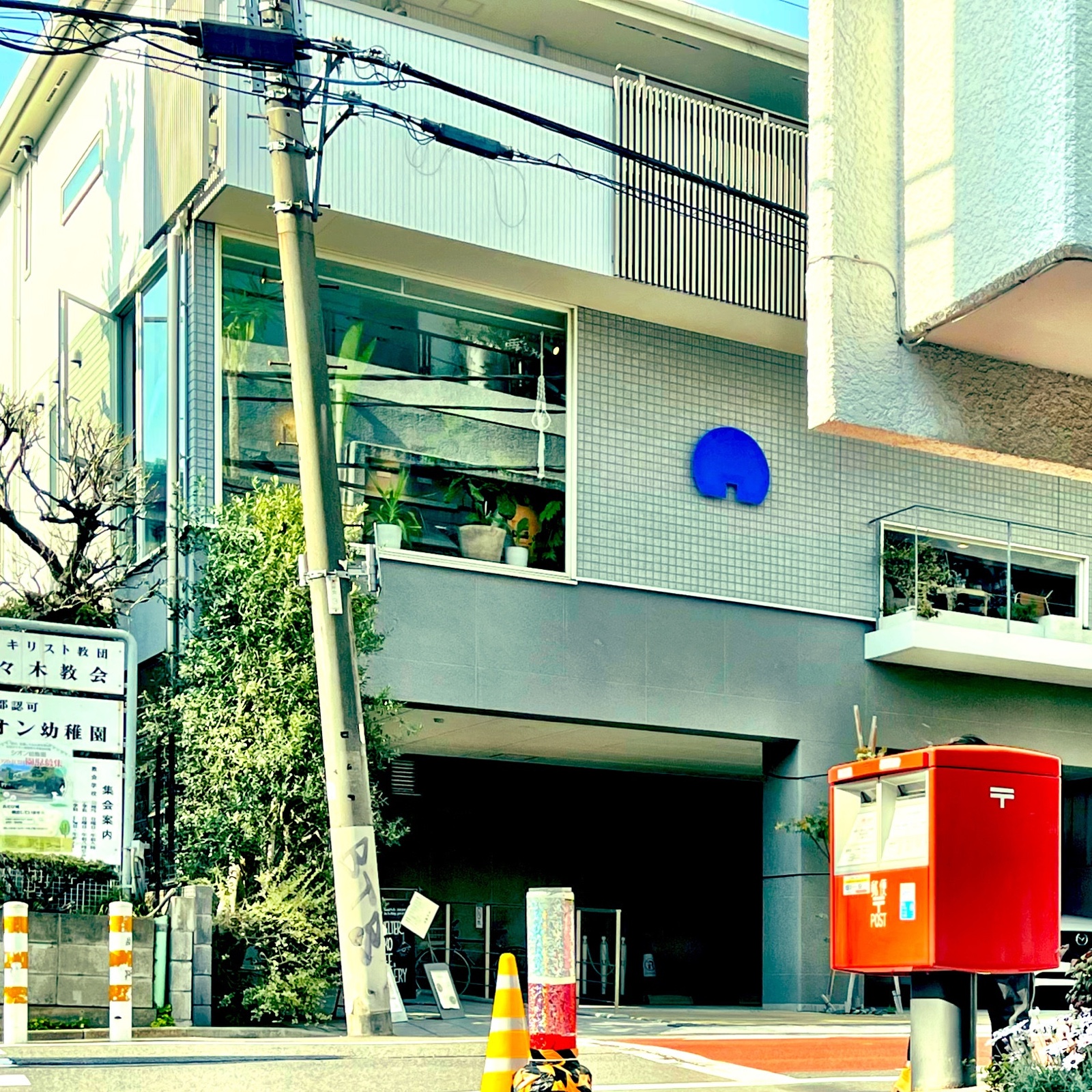 ムーンテッド(MoonTed)の日記より、2階にカフェ「Shelter KUKO cafe&gallery」が入る建物。窓辺に植物、手前に赤いポスト