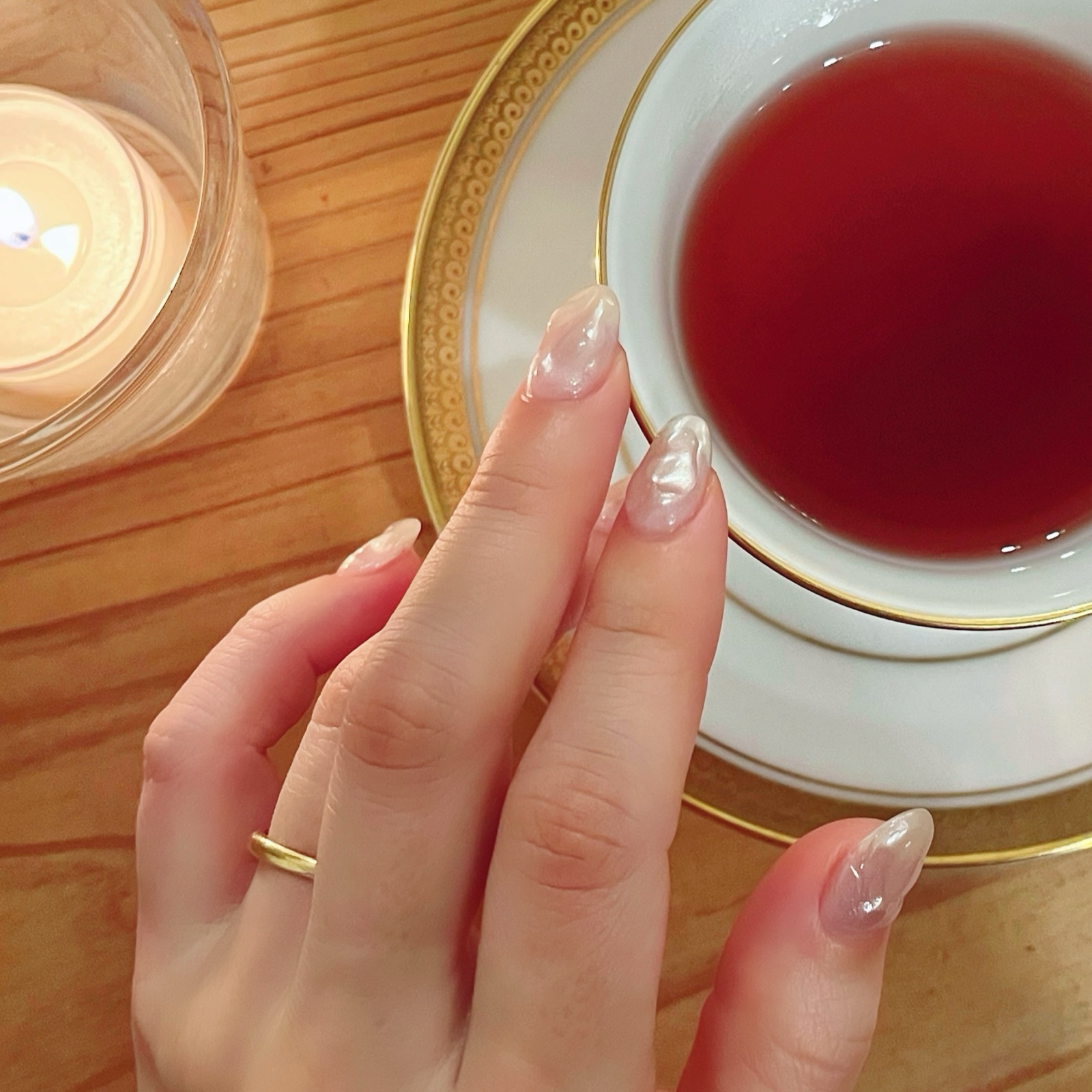 MoonTed Diary: A guest's hand with pale pink pearly nails on her wedding day, beside a gold-rimmed cup of tea and a candle