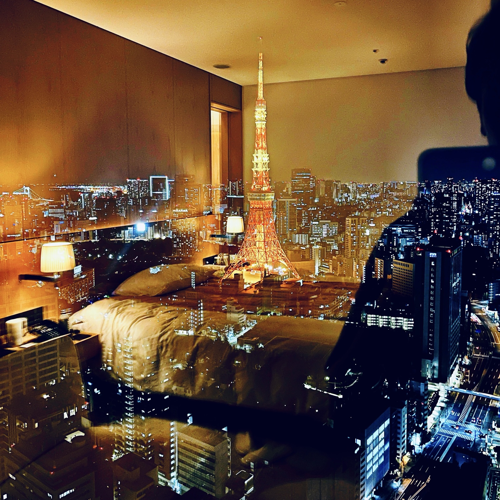 MoonTed Diary: Tokyo Tower at night seen from a hotel suite window, with the bed and lamp reflected in the glass