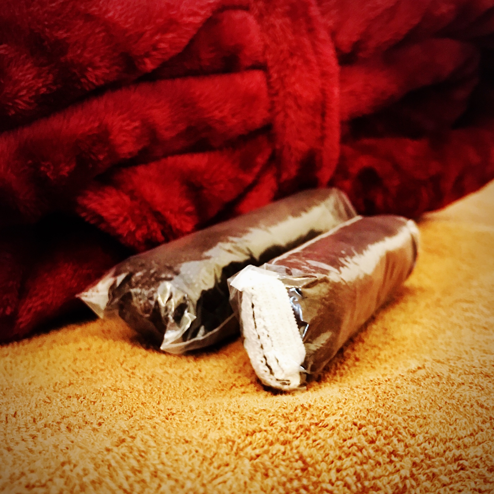 ムーンテッド(MoonTed)の日記より、個包装された使い捨ての紙ショーツ2つ。茶色のタオルの上、奥に赤いガウン