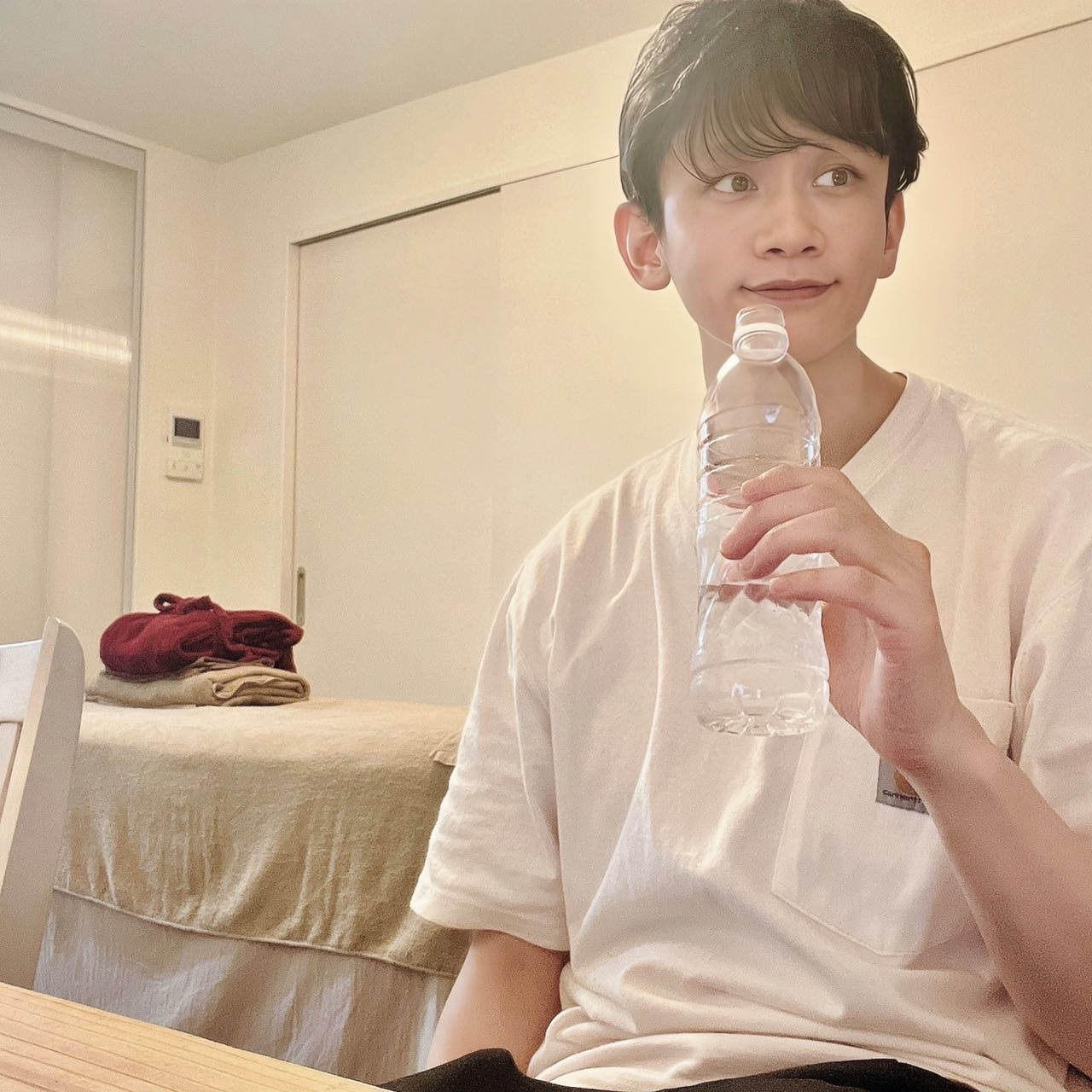 ムーンテッド(MoonTed)の日記より、ペットボトルの水を手に、横を見て微笑むムーンテッド(MoonTed)のセラピストAKI。奥に施術台