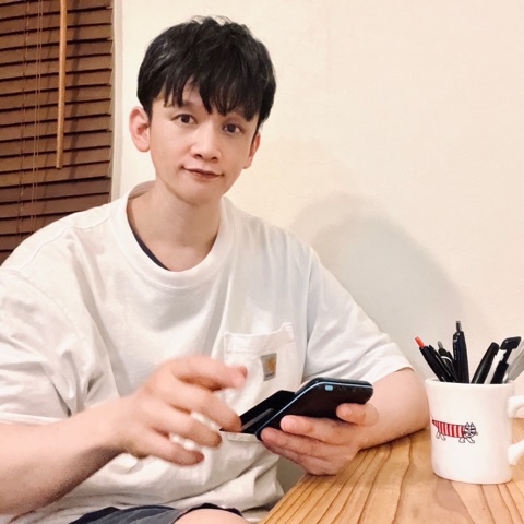 ムーンテッド（MoonTed）の日記より、スマートフォンを手に机に座るムーンテッド（MoonTed）のセラピストAKI。そばにペン立てのマグカップ