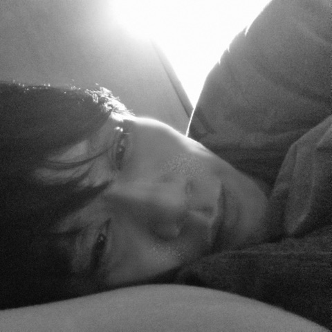 ムーンテッド（MoonTed）の日記より、枕に顔をうずめて横になるムーンテッド（MoonTed）のセラピストAKI。逆光のモノクロ写真
