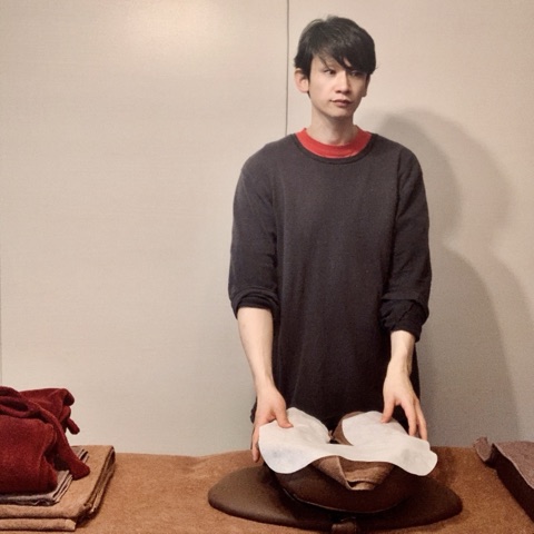 ムーンテッド（MoonTed）の日記より、施術台の穴枕に紙のフェイスカバーを敷くムーンテッド（MoonTed）のセラピストAKI。こげ茶のニット姿